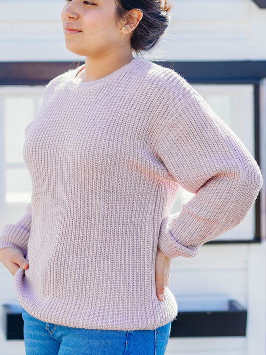 This image of a woman features the product Women's Knit Sweater – Light Purple. This crew neck sweater comes in a light purple color.