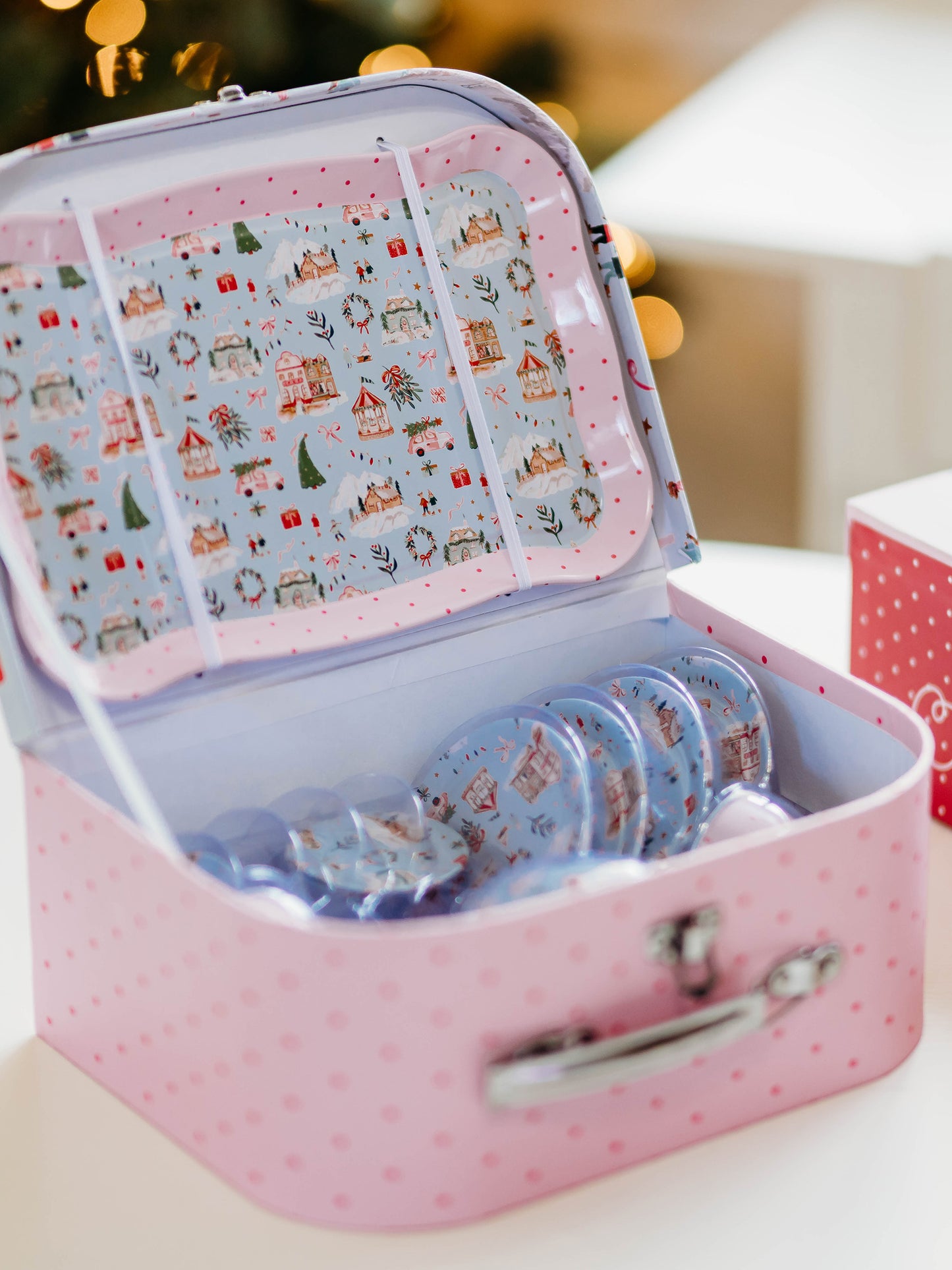 The serving tray, plates, and kettle features our pattern Christmas Village. The cups are a pattern of pink polka dots on light pink.