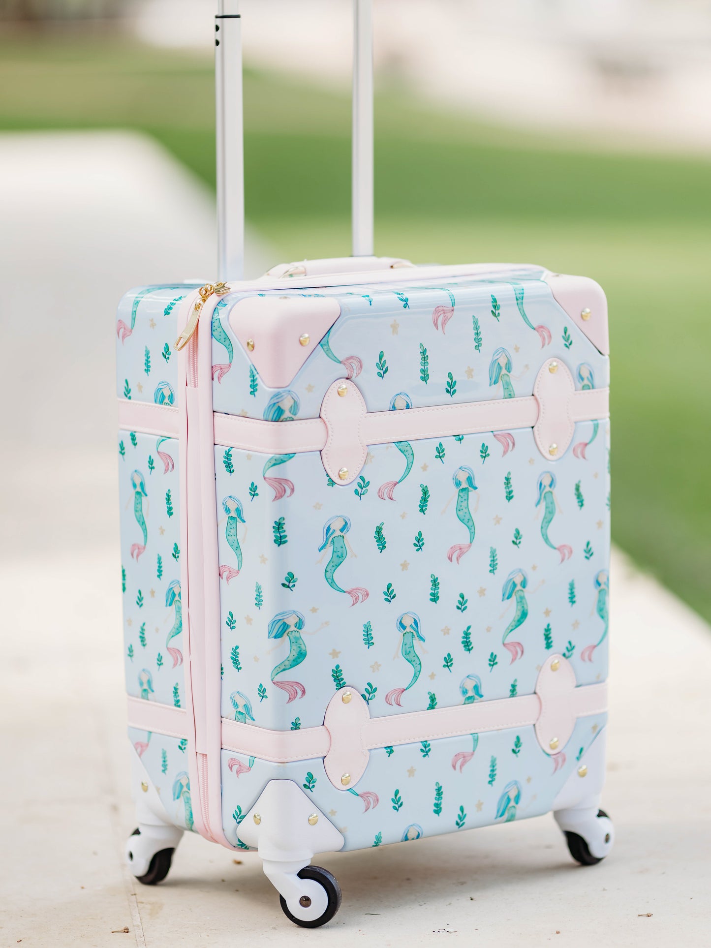 Lennon Traveling Luggage – Sea Princess. The outside of this luggage is a pattern of mermaids and little green sea plants on a pale blue background. The inside lining is a pattern of pale blue starfish like stars on a blue background.