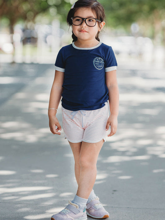 This image of a girl features the product Graphic Tee - SweetHoney Navy. A short sleeve shirt with a cute graphic that says Sweet Honey family owned clothing. Est. 2012